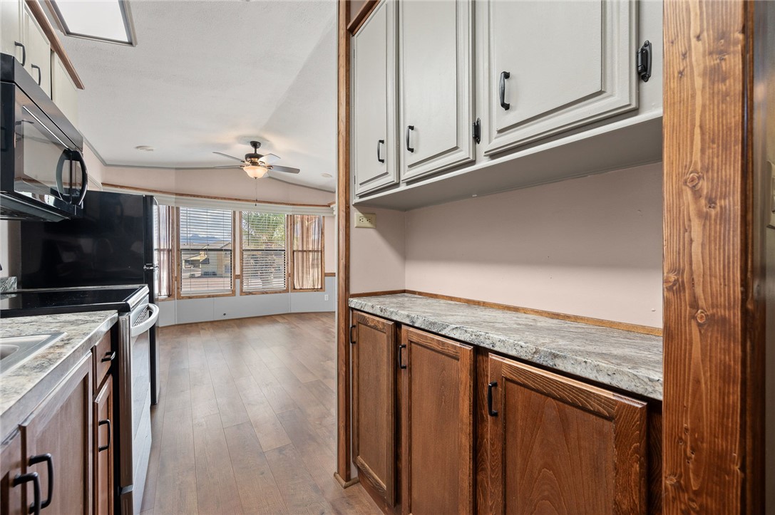 2000 Ramar Road, Unit 587 Bullhead City, AZ 86442 - Photo 27 of 79 Kitchen featuring vaulted ceiling, stainless steel range with electric stovetop, black microwave, dark wood-style floors, and light countertops