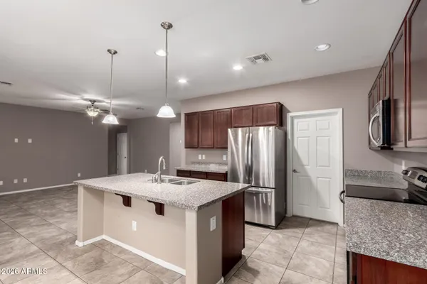 a kitchen with stainless steel appliances granite countertop a sink a stove a refrigerator and a chandelier