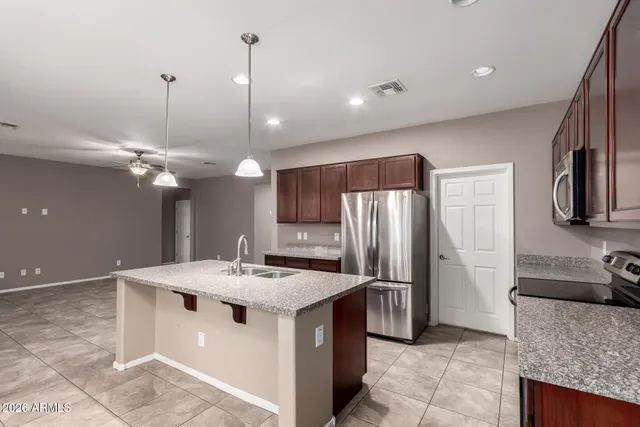 a kitchen with stainless steel appliances granite countertop a sink a stove a refrigerator and a chandelier