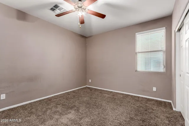 en empty room with windows and chandelier fan