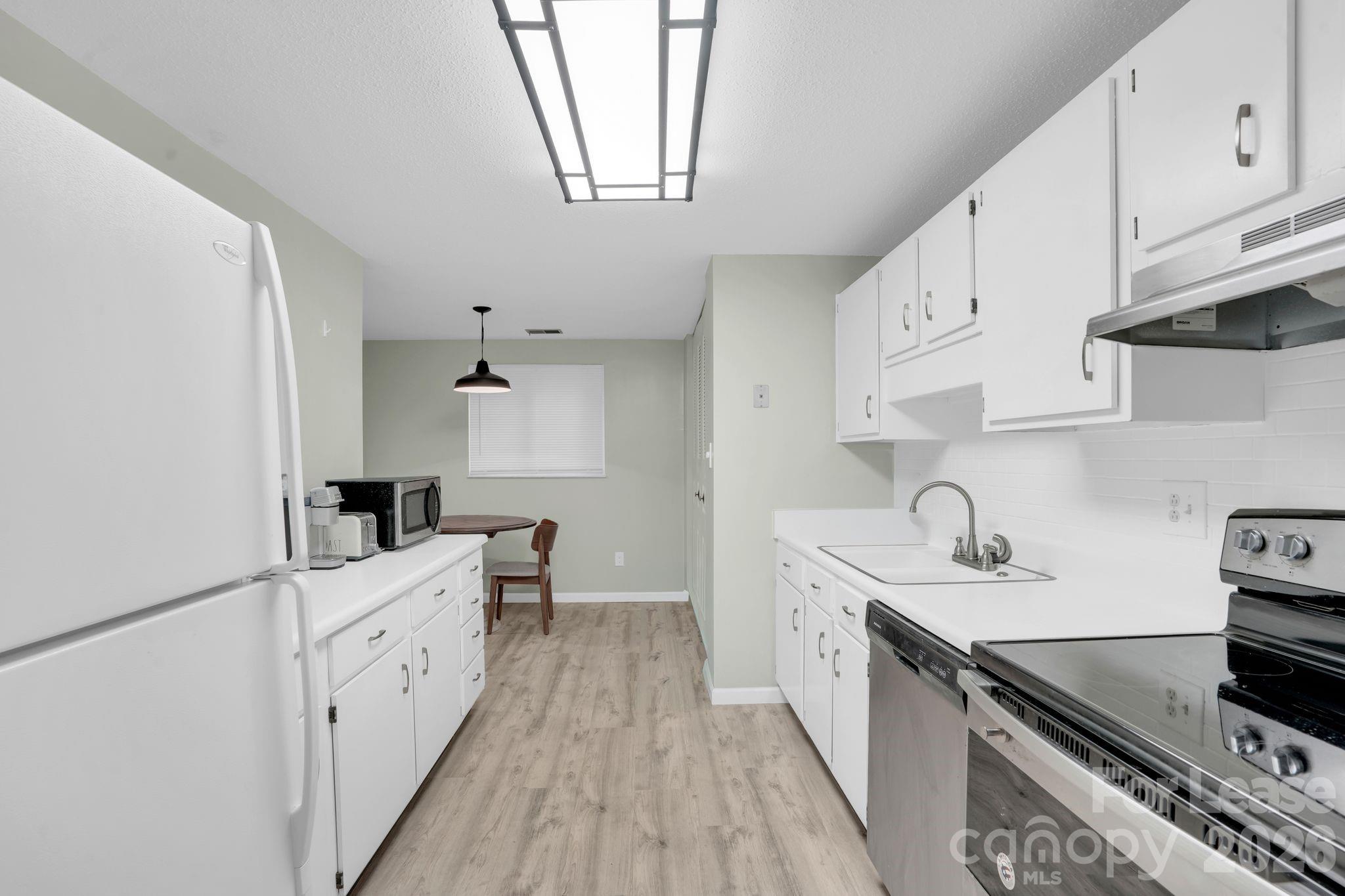 2427 Studley Road Charlotte, NC 28212 - Photo 14 of 30 a kitchen with white cabinets stove and sink