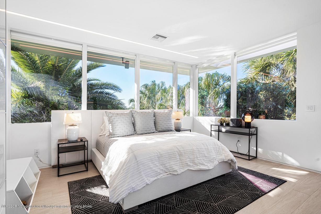 2299 Ibis Isle Road East Palm Beach, FL 33480 - Photo 33 of 37 a bedroom with a bed a table and large windows