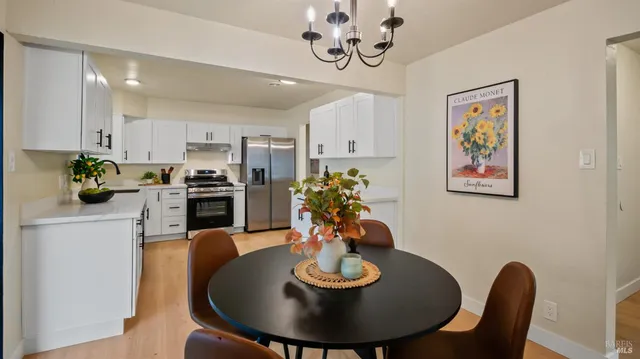 a view of a dining room with furniture a kitchen and chandelier