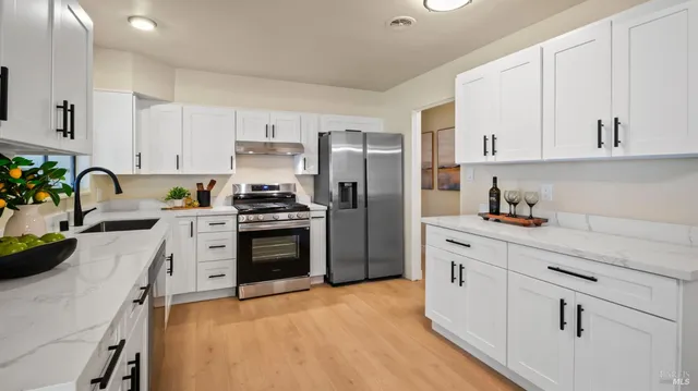 a kitchen with granite countertop a refrigerator stove and white cabinets