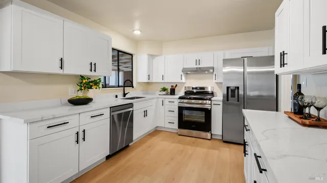 a kitchen with cabinets stainless steel appliances and wooden floor