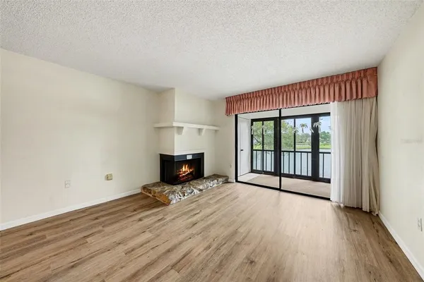 a view of empty room with wooden floor and fireplace