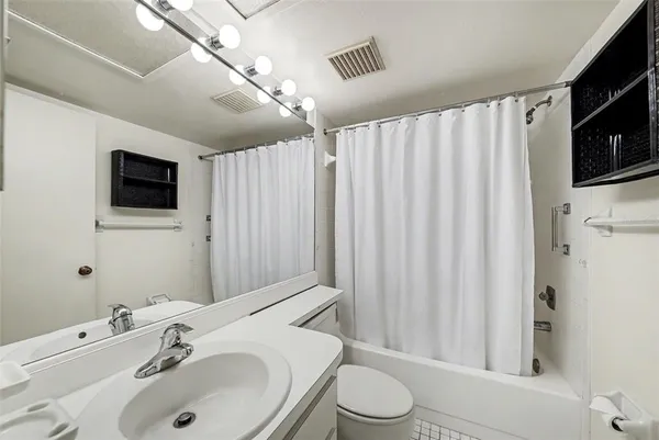 a bathroom with a sink toilet a mirror and shower curtain