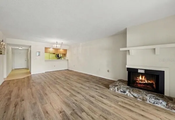 a view of an empty room with a fireplace and wooden floor
