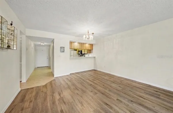 a view of a big room with wooden floor and a kitchen