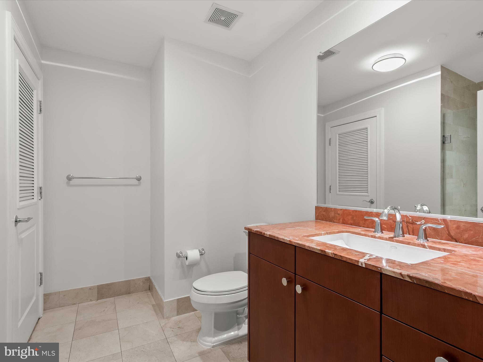 2425 L Street Northwest, Unit 239 Washington, DC 20037 - Photo 30 of 43 a bathroom with a sink a toilet a mirror and vanity