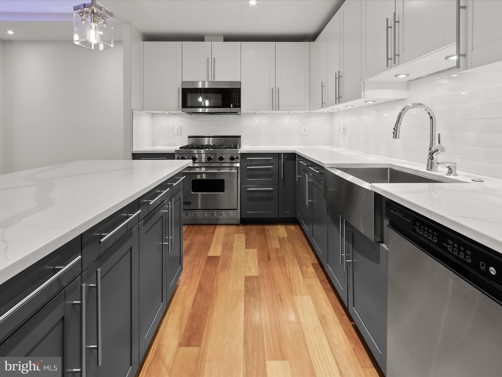 2425 L Street Northwest, Unit 239 Washington, DC 20037 - Photo 10 of 43 a kitchen with stainless steel appliances a sink dishwasher a stove top oven a refrigerator with cabinets and wooden floor