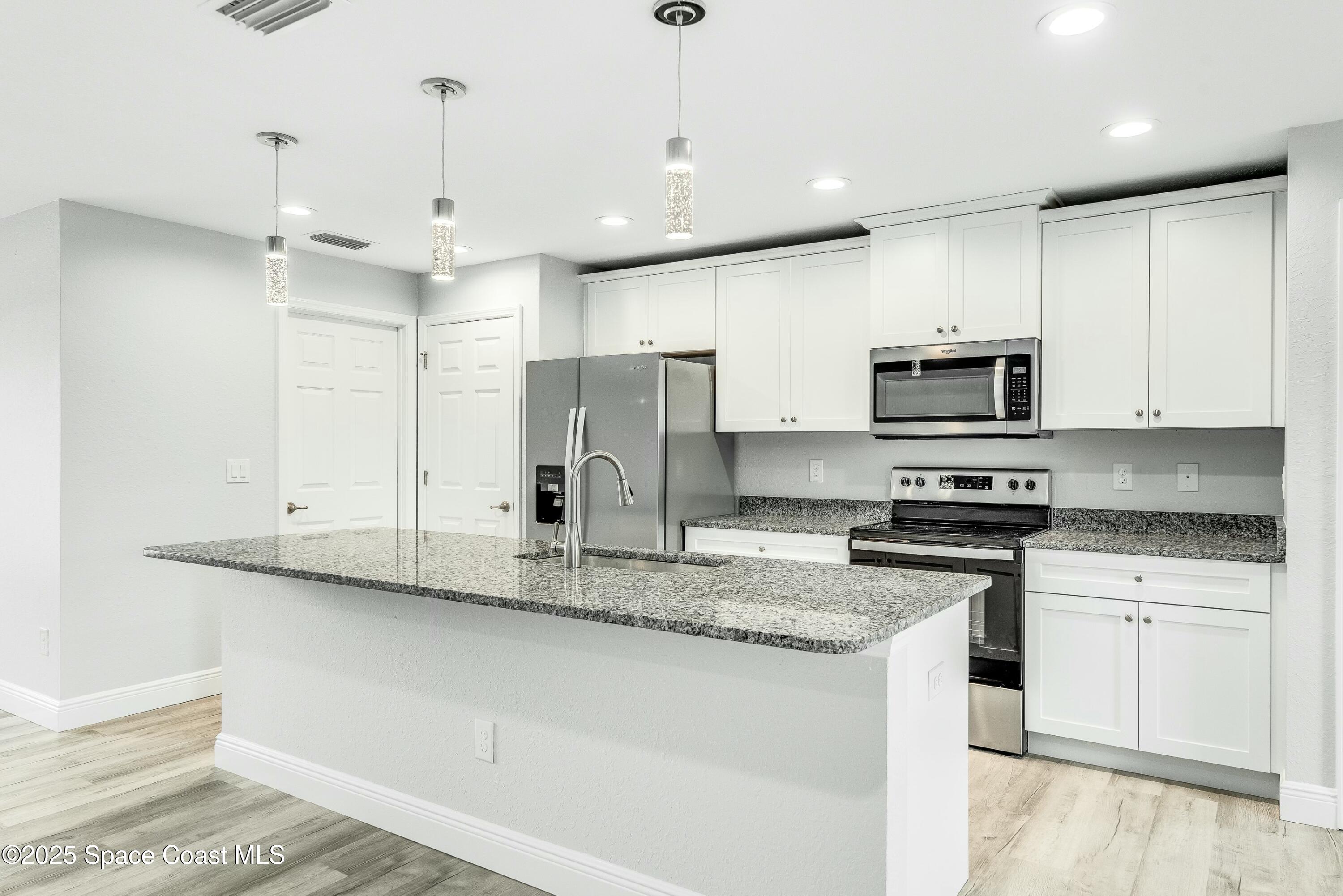 1341 Defender Street Northwest Palm Bay, FL 32907 - Photo 15 of 38 a kitchen with stainless steel appliances granite countertop a sink a stove a refrigerator and cabinets