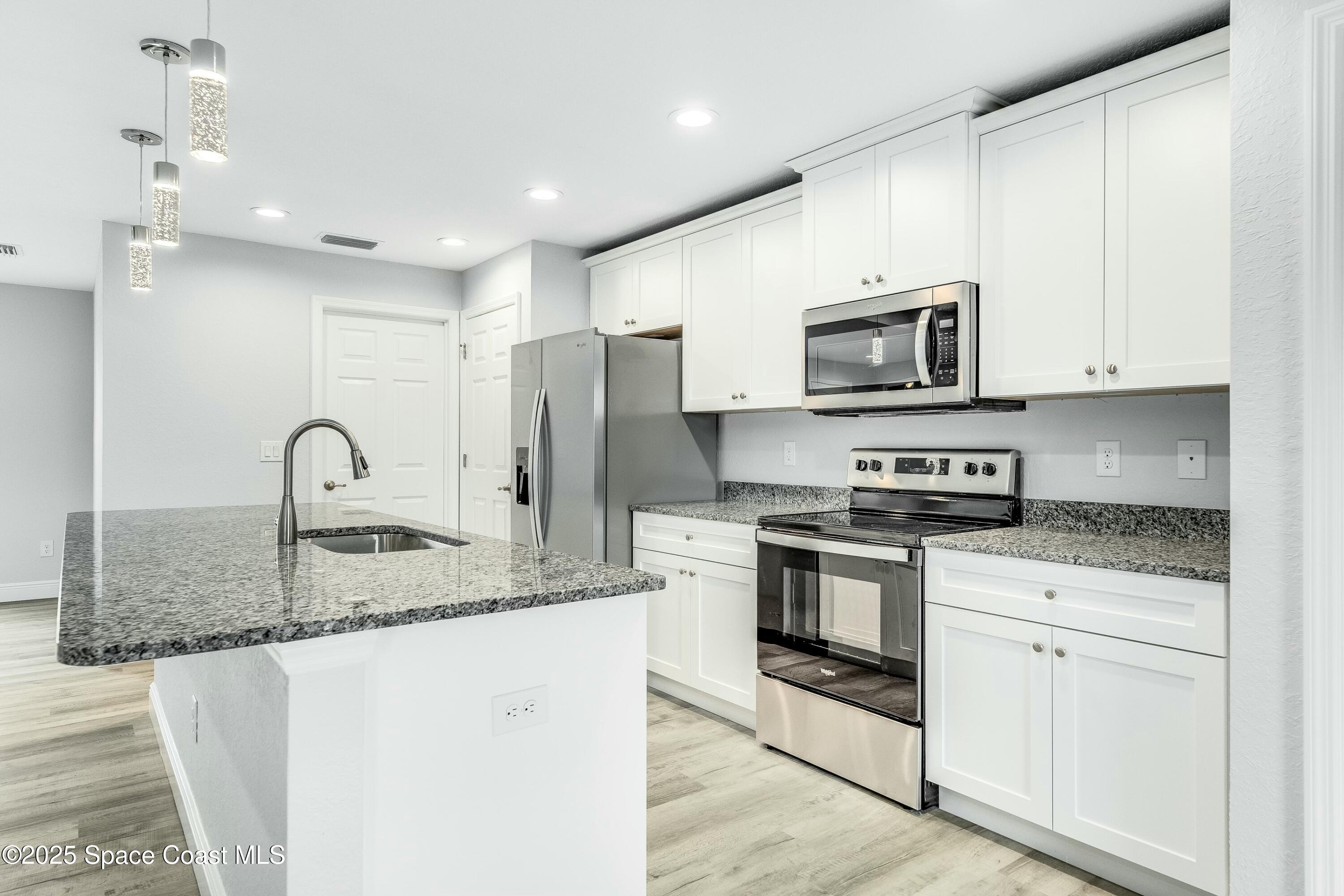 1341 Defender Street Northwest Palm Bay, FL 32907 - Photo 16 of 38 a kitchen with stainless steel appliances granite countertop a stove a sink and a refrigerator