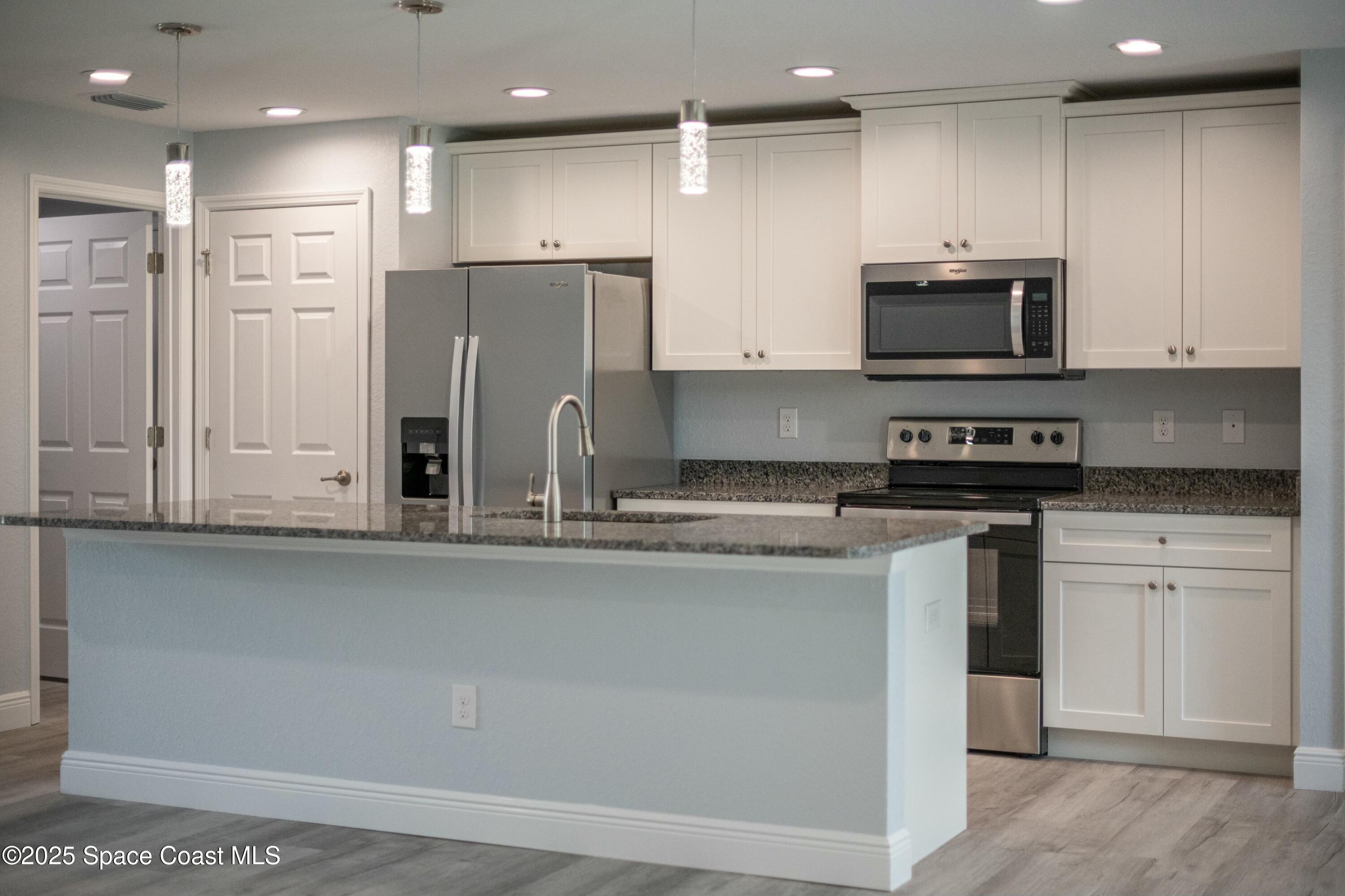 1341 Defender Street Northwest Palm Bay, FL 32907 - Photo 18 of 38 a kitchen with stainless steel appliances granite countertop a refrigerator and a stove top oven