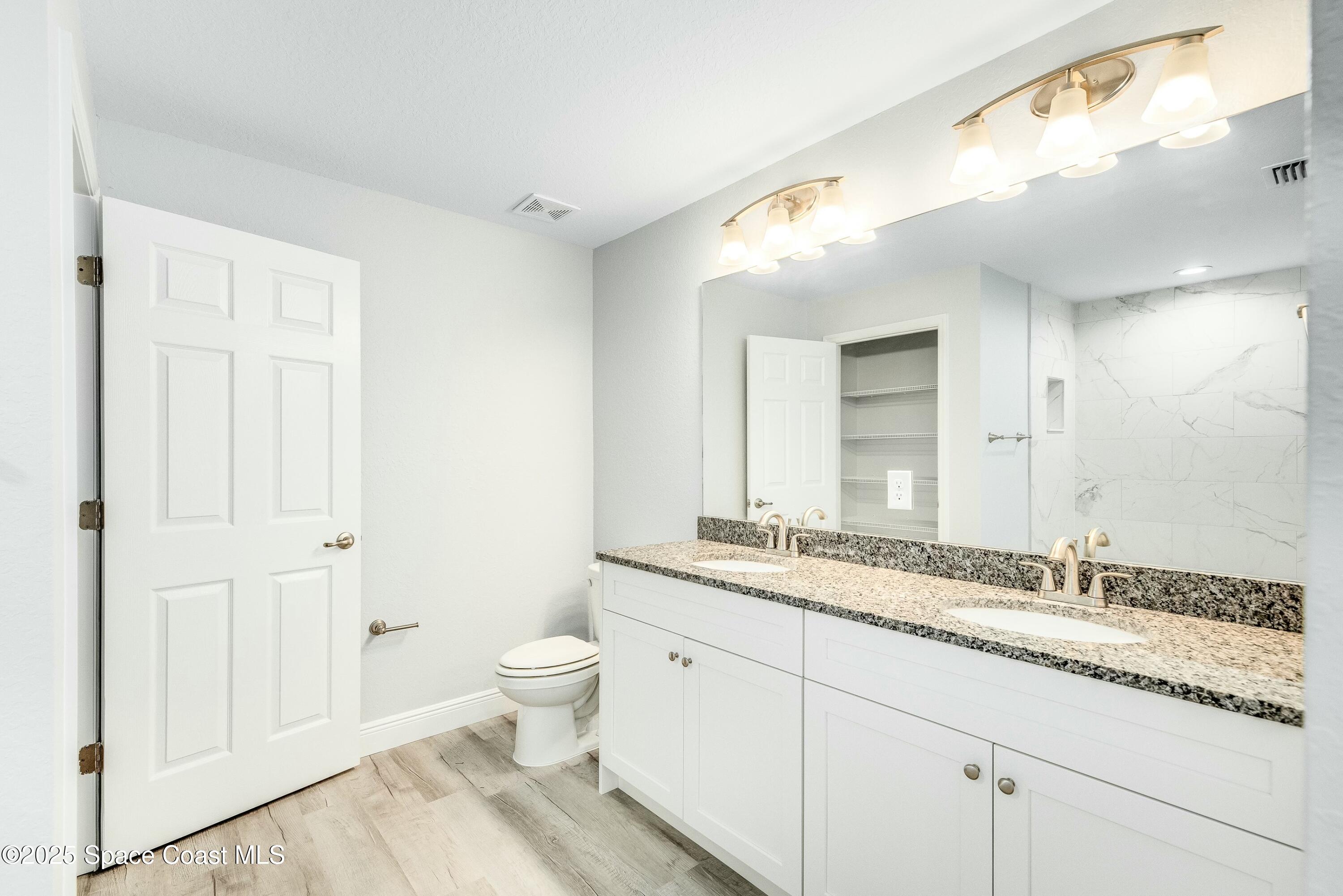 1341 Defender Street Northwest Palm Bay, FL 32907 - Photo 25 of 38 a bathroom with a granite countertop sink a toilet and a mirror