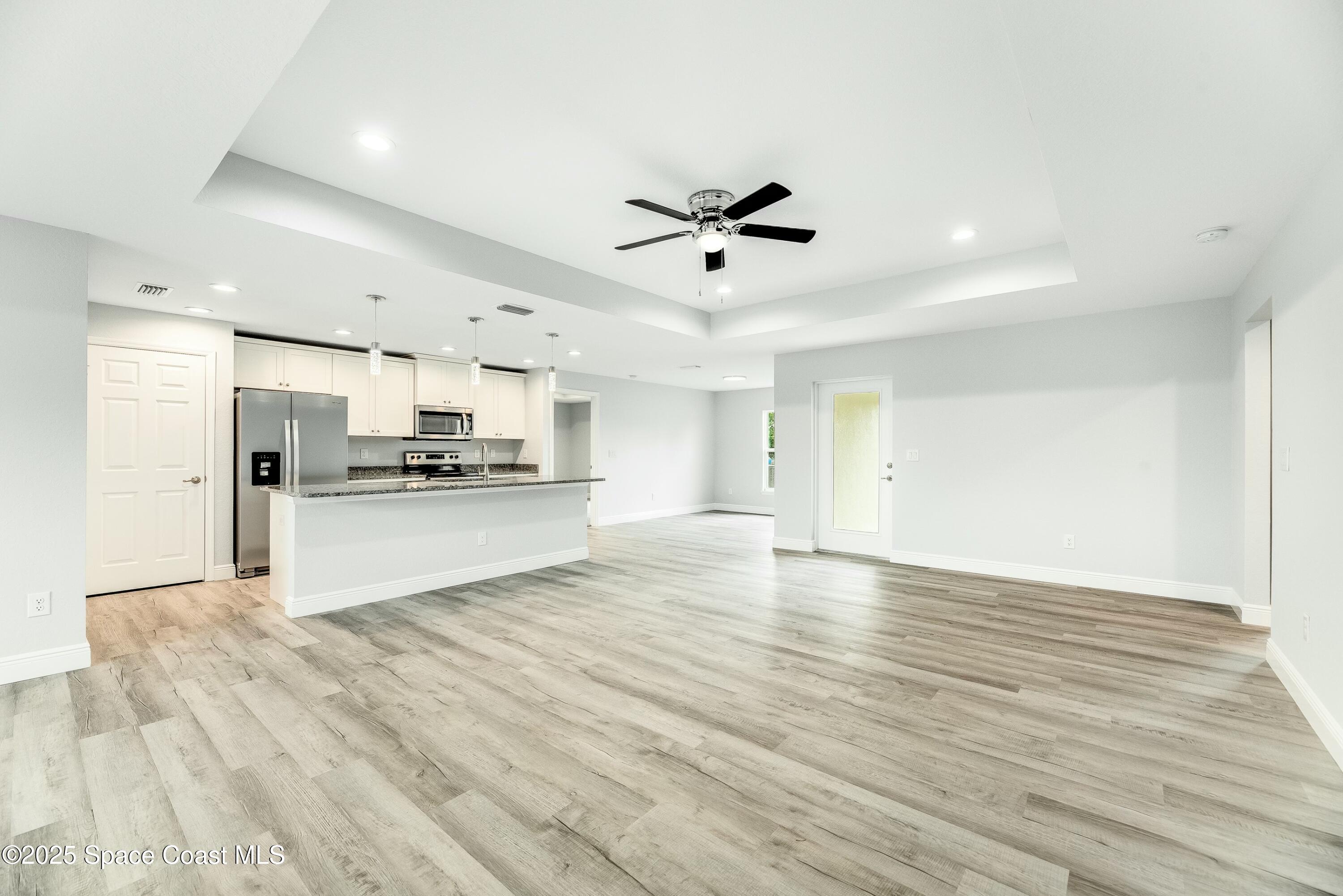 1341 Defender Street Northwest Palm Bay, FL 32907 - Photo 8 of 38 a view of kitchen with wooden floor and refrigerator