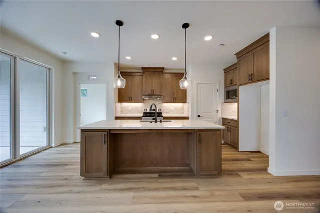 a large kitchen with stainless steel appliances a large counter top space cabinets and wooden floor