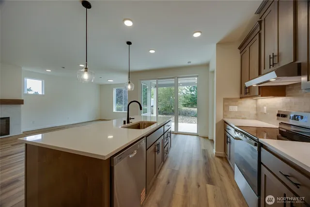 a kitchen with a sink stainless steel appliances and wooden floor