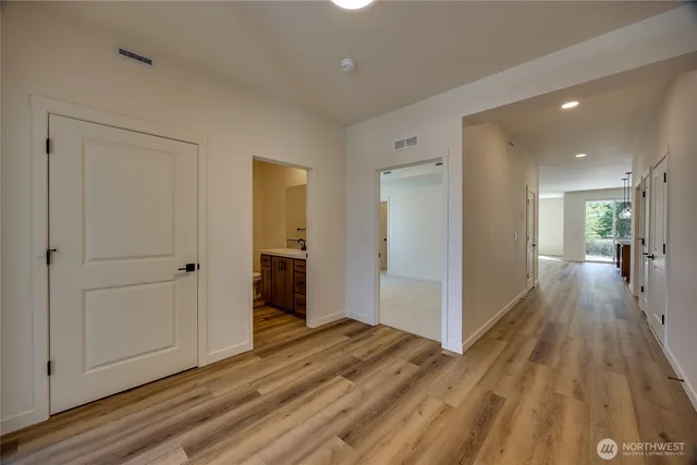 a view of a hallway with wooden floor and closet area
