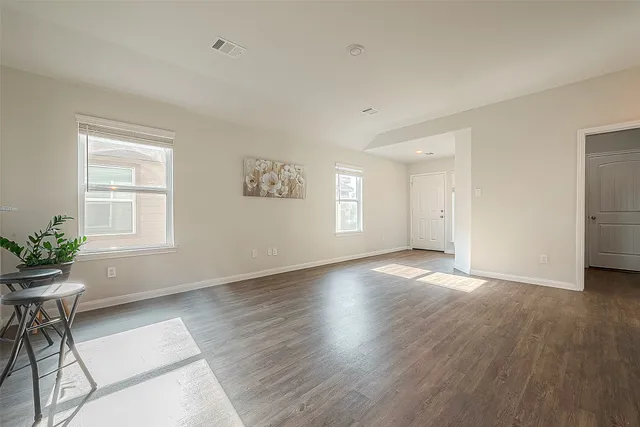a view of an empty room with a window and wooden floor