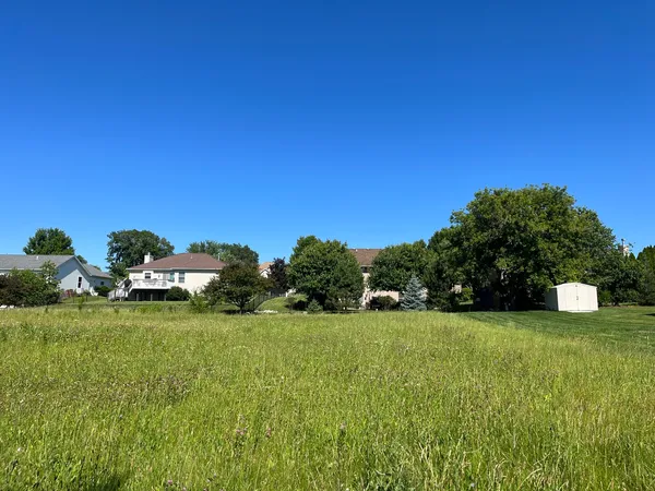 a view of a field with of trees in the background