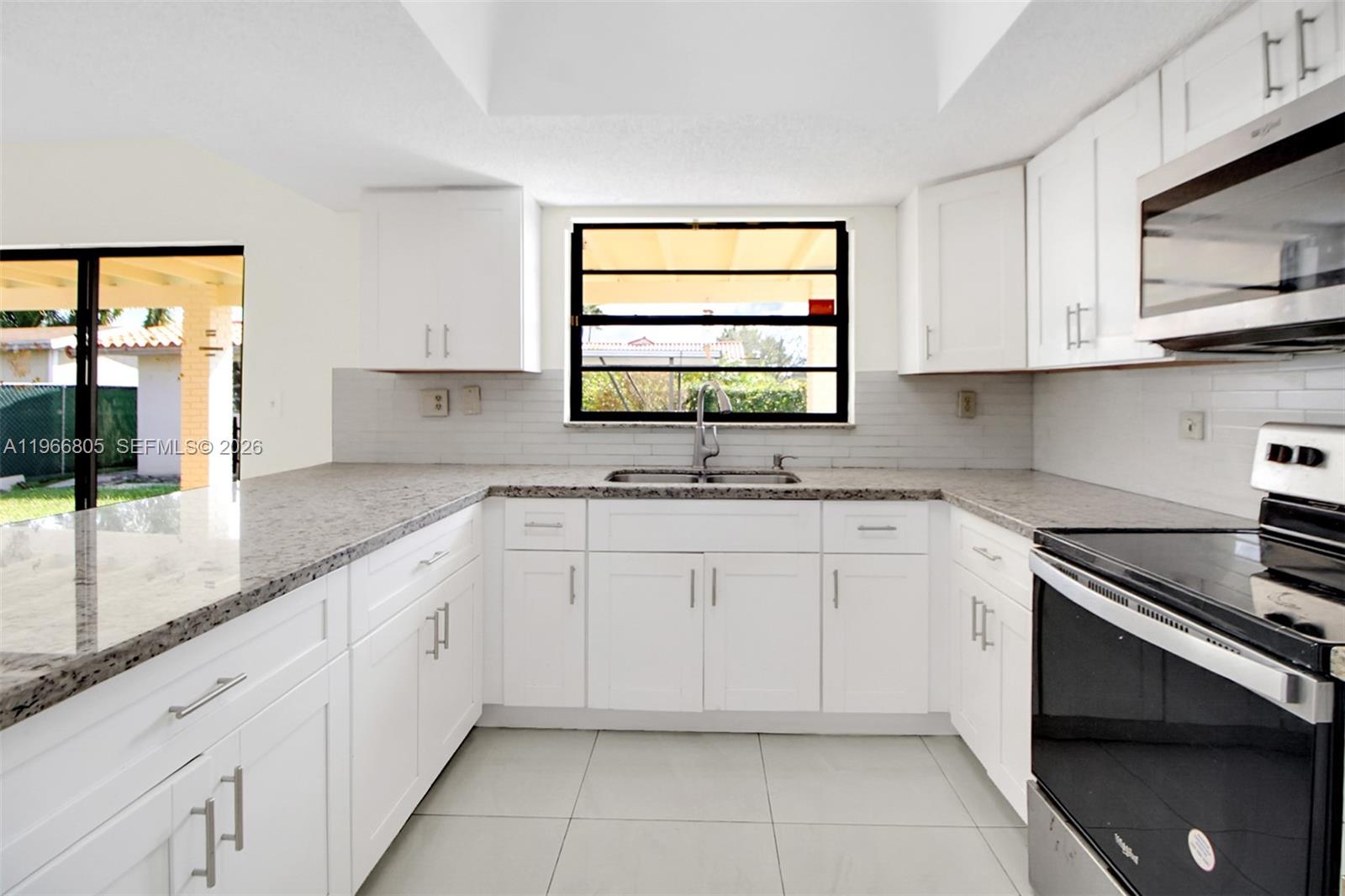 13844 Southwest 15th Street Miami, FL 33184 - Photo 5 of 31 a kitchen with granite countertop white cabinets white appliances and sink
