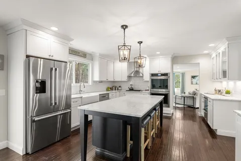 a kitchen with stainless steel appliances a refrigerator a sink dishwasher a stove and white cabinets with wooden floor
