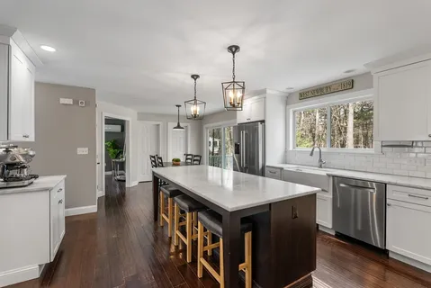 a open kitchen with stainless steel appliances granite countertop a kitchen island a stove a table and chairs in it