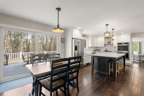 a dining room with wooden floor a chandelier a wooden table and chairs