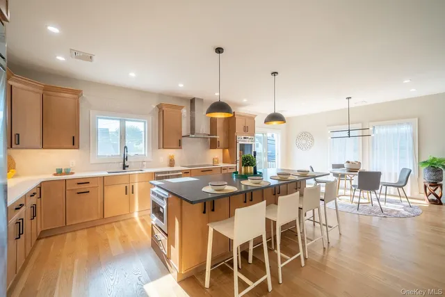 a kitchen with stainless steel appliances granite countertop a stove a sink dishwasher a dining table and chairs with wooden floor