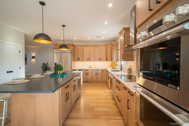 a large kitchen with kitchen island a large counter top a stove a sink and a chandelier