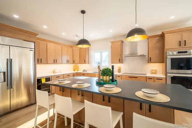 a kitchen with stainless steel appliances granite countertop a sink a stove a refrigerator and chairs