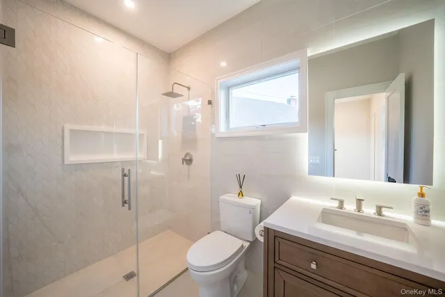 a bathroom with a granite countertop sink toilet a mirror and shower