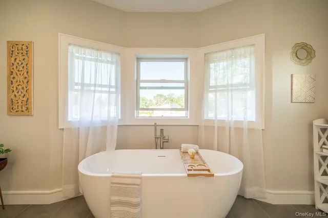 a white bath tub sitting in a bathroom next to a window