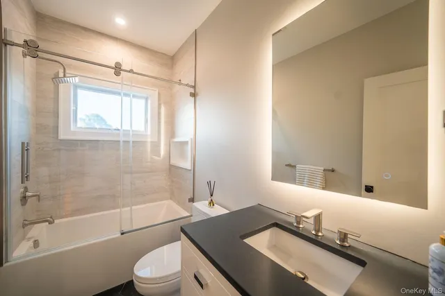 a bathroom with a granite countertop sink toilet a mirror and shower