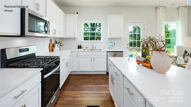 a kitchen with stainless steel appliances a white stove top oven a sink dishwasher and white cabinets next to a window