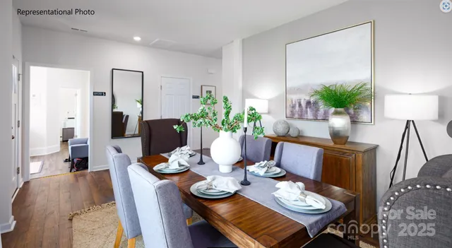 a view of a dining room with furniture a potted plant and wooden floor