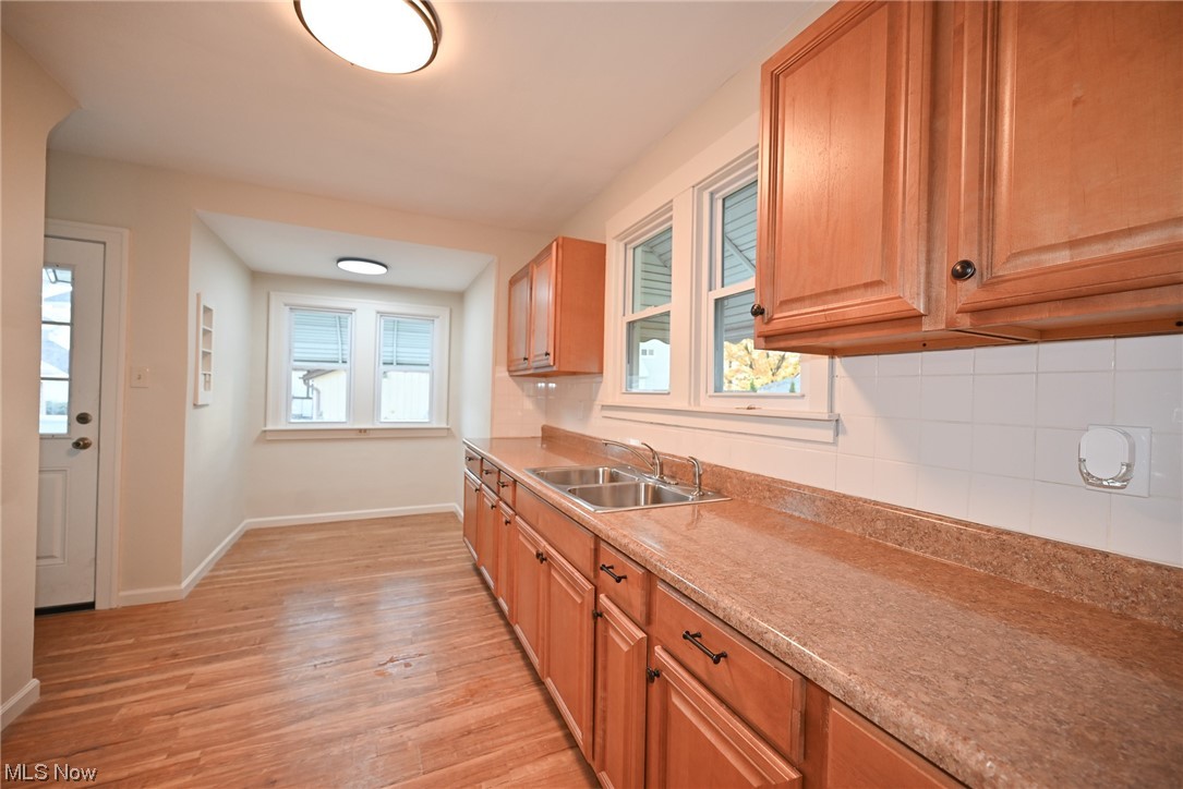 3832 Silsby Road Cleveland, OH 44111 - Photo 10 of 21 Kitchen featuring light hardwood / wood-style floors, sink, and backsplash