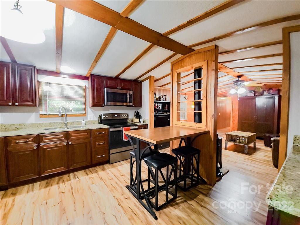 278 Pipers Neck Rutherfordton, NC 28139 - Photo 15 of 42 a kitchen with stainless steel appliances granite countertop a stove a refrigerator a sink a dining table and chairs with wooden floor