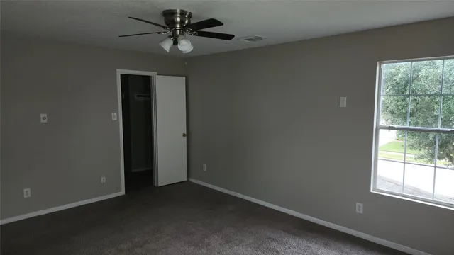 an empty room with a window and a fan