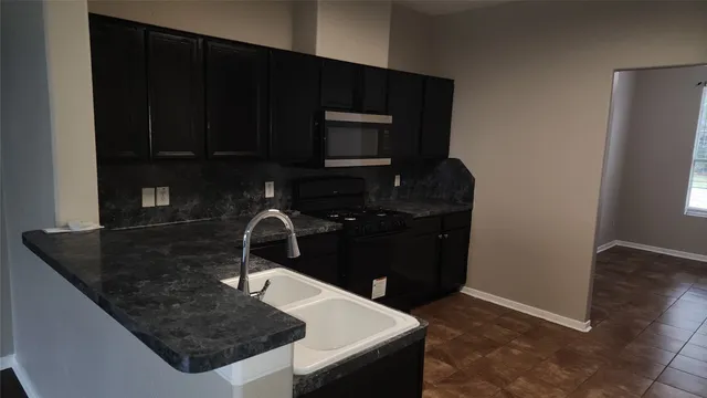 a kitchen with a sink and a stove top oven with wooden floor
