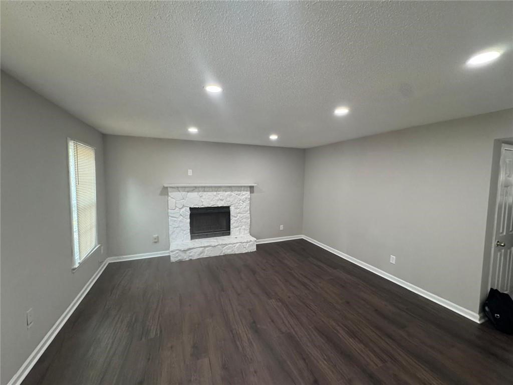 385 Holly Ridge Drive Northwest, Unit 5 Lilburn, GA 30047 - Photo 3 of 10 an empty room with wooden floor and fireplace