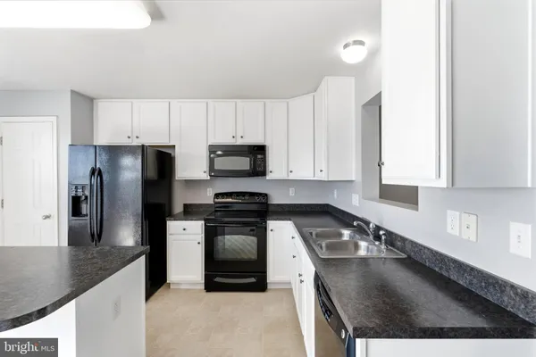 a kitchen with stainless steel appliances granite countertop a sink a stove a refrigerator a counter space and cabinets