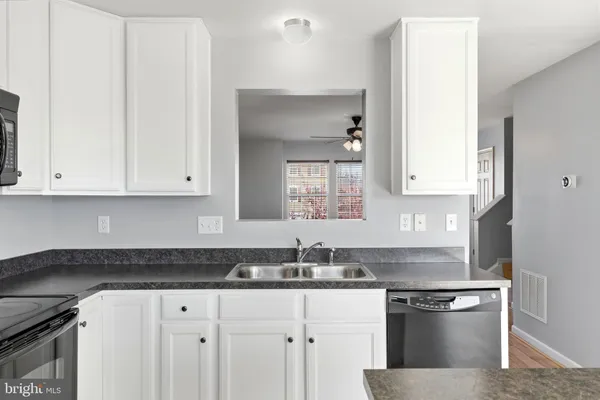 a kitchen with granite countertop white cabinets and a sink