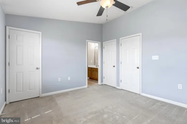 an empty room with chandelier fan and closet area