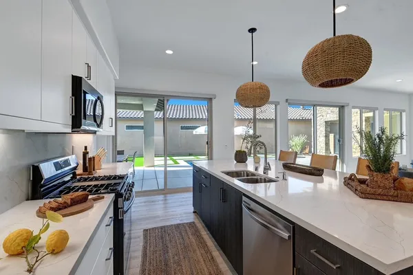 a kitchen with stainless steel appliances granite countertop a sink a stove and a wooden floors