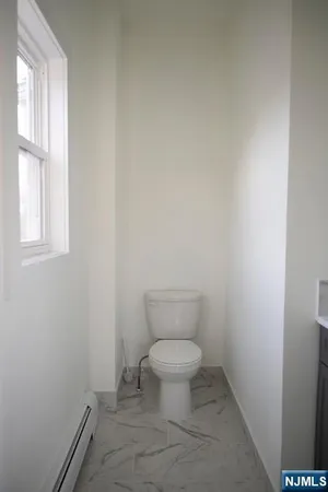 a white toilet sitting in a bathroom next to a window