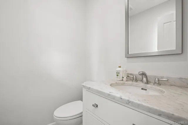 a bathroom with a granite countertop toilet sink mirror and vanity