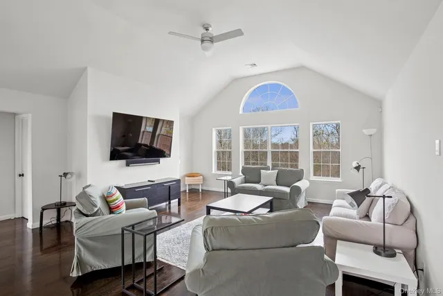 a living room with furniture a flat screen tv and a window
