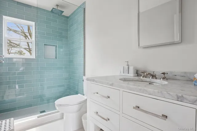 a bathroom with a granite countertop toilet a sink a mirror and a shower